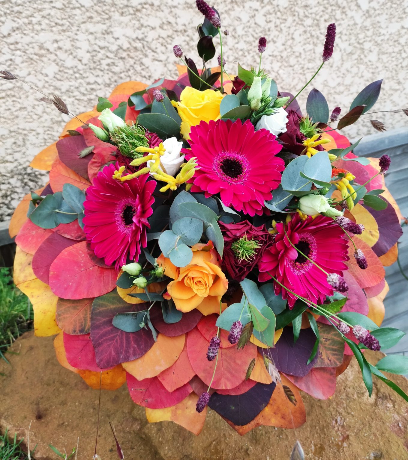 bouquet au ton automnale sur une structure en feuilles d'arbuste naturelles